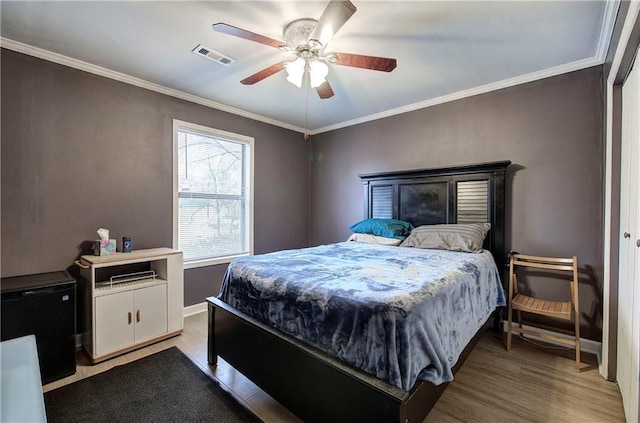 bedroom with crown molding, wood-type flooring, and ceiling fan