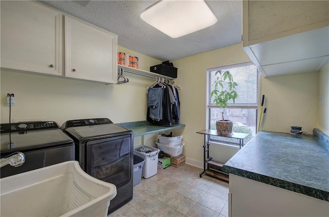 laundry area with washer and dryer, a textured ceiling, light tile patterned flooring, sink, and cabinets