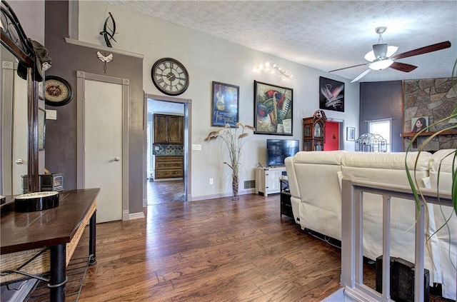 living room featuring ceiling fan, dark hardwood / wood-style flooring, and a textured ceiling