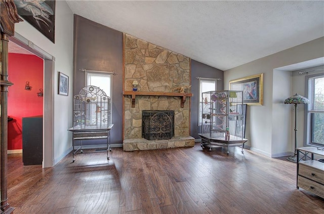 unfurnished living room featuring a fireplace, vaulted ceiling, a wealth of natural light, and hardwood / wood-style floors