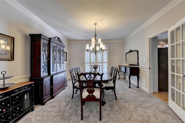 carpeted dining area with ornamental molding and a chandelier