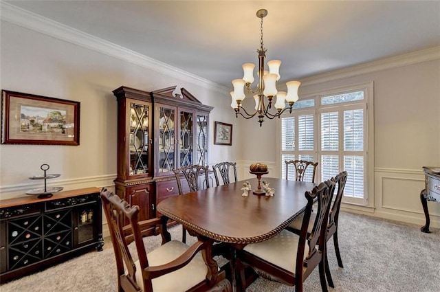 dining area featuring crown molding, an inviting chandelier, and light colored carpet