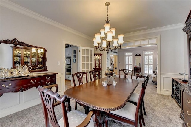 carpeted dining area with an inviting chandelier and ornamental molding