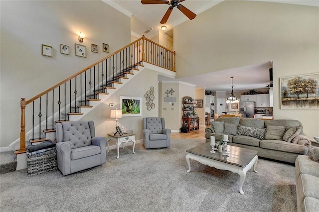 living room with ceiling fan with notable chandelier, a towering ceiling, and carpet floors