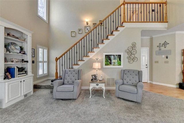 living area featuring hardwood / wood-style flooring, ornamental molding, and a high ceiling