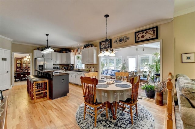 dining space with light hardwood / wood-style floors, ornamental molding, and sink