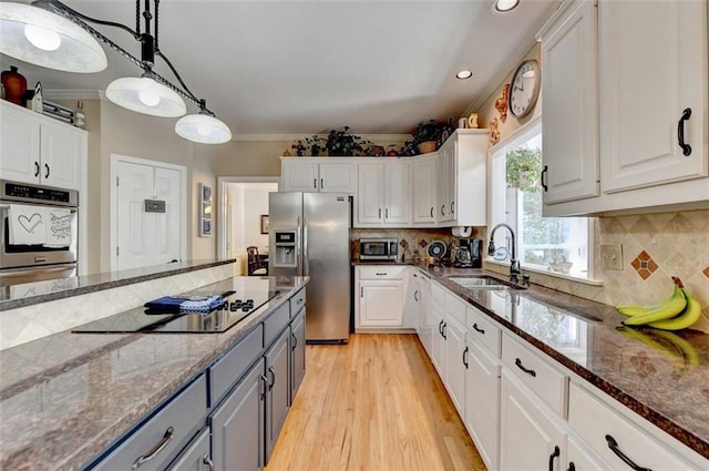 kitchen featuring stainless steel appliances, sink, pendant lighting, and white cabinets