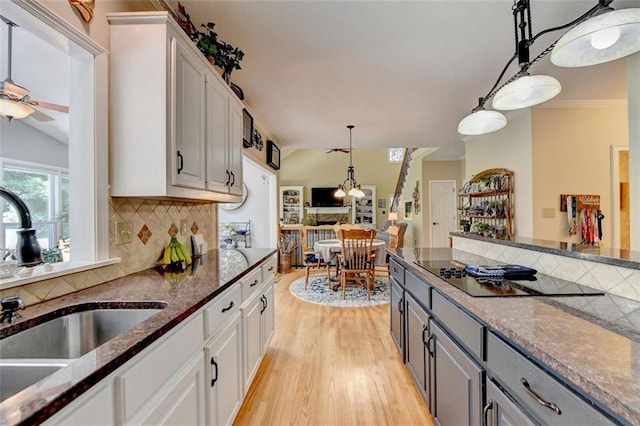 kitchen featuring decorative backsplash, black electric stovetop, hanging light fixtures, gray cabinets, and white cabinetry