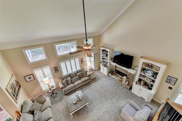 living room with ornamental molding, carpet flooring, a fireplace, a towering ceiling, and ceiling fan