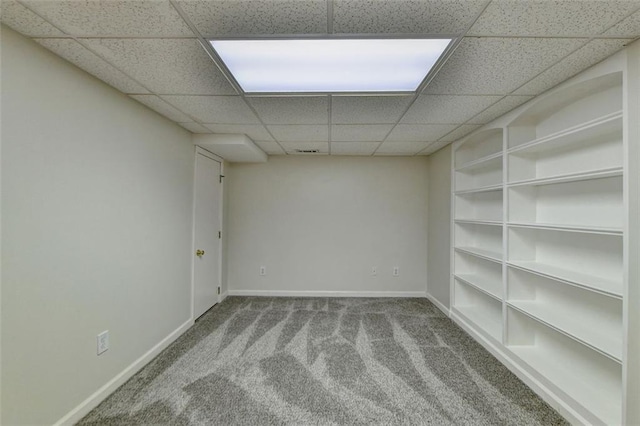 spare room featuring light carpet and a paneled ceiling