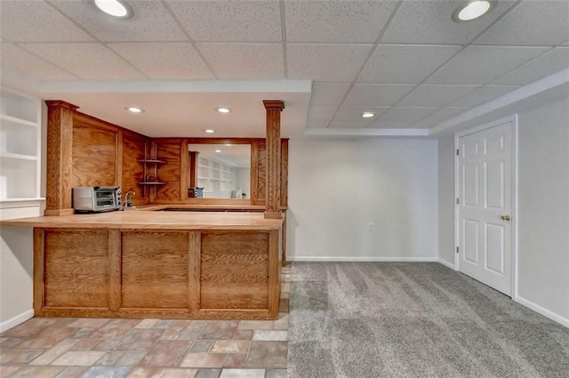 kitchen with decorative columns, a drop ceiling, and light colored carpet