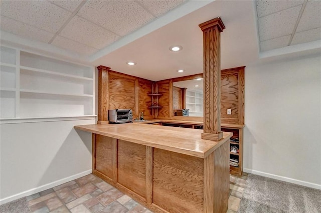 kitchen with a drop ceiling, kitchen peninsula, and decorative columns