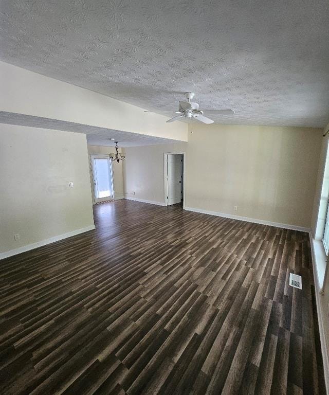 unfurnished living room with ceiling fan with notable chandelier, dark hardwood / wood-style floors, and a textured ceiling