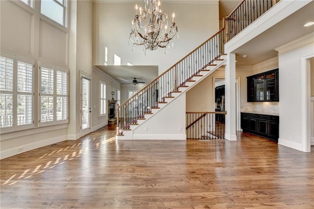 foyer with stairs, ornamental molding, wood finished floors, and baseboards