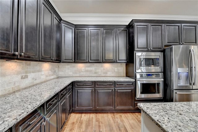 kitchen featuring light stone counters, stainless steel appliances, ornamental molding, light wood-type flooring, and backsplash