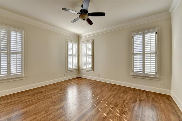 spare room featuring ornamental molding, baseboards, and wood finished floors