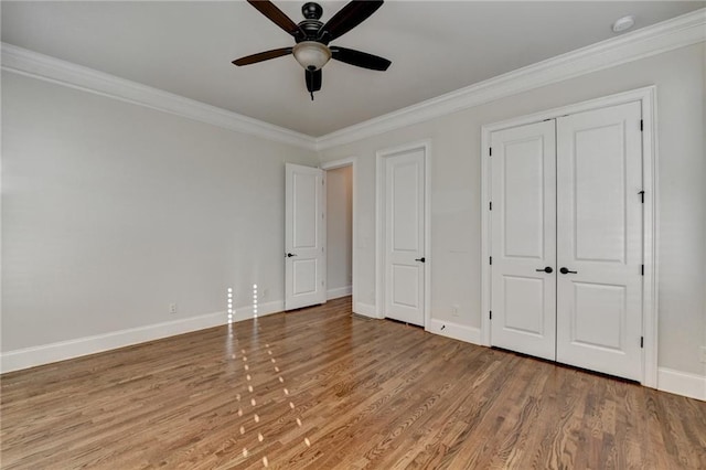 unfurnished bedroom with ceiling fan, crown molding, baseboards, and wood finished floors