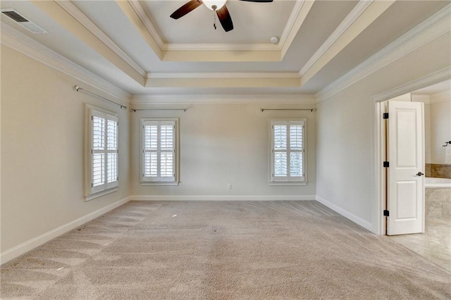 carpeted spare room with baseboards, a tray ceiling, visible vents, and crown molding