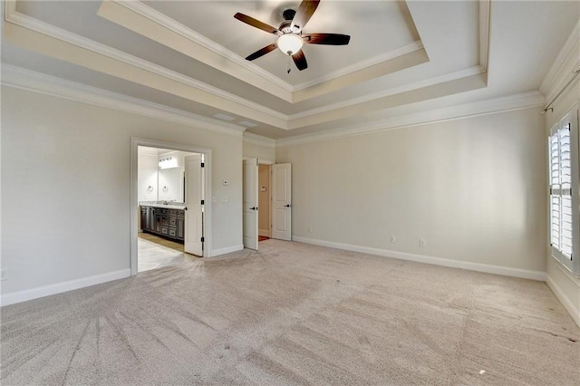 unfurnished bedroom featuring crown molding, a tray ceiling, carpet, and baseboards