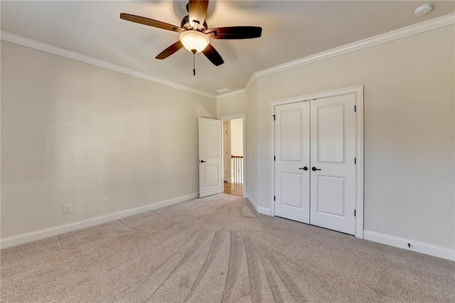 unfurnished bedroom featuring carpet floors, a closet, baseboards, and crown molding