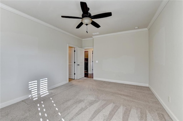 spare room with carpet floors, ceiling fan, baseboards, and ornamental molding