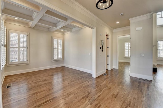 empty room featuring coffered ceiling, wood finished floors, visible vents, and baseboards