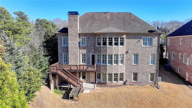 rear view of house with brick siding, a chimney, central AC unit, a wooden deck, and stairs