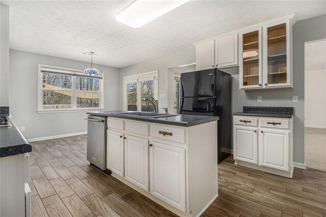 kitchen with a sink, dark countertops, dark wood-type flooring, and dishwasher