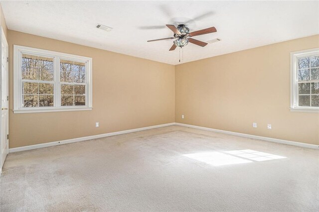 spare room featuring light carpet, ceiling fan, visible vents, and baseboards