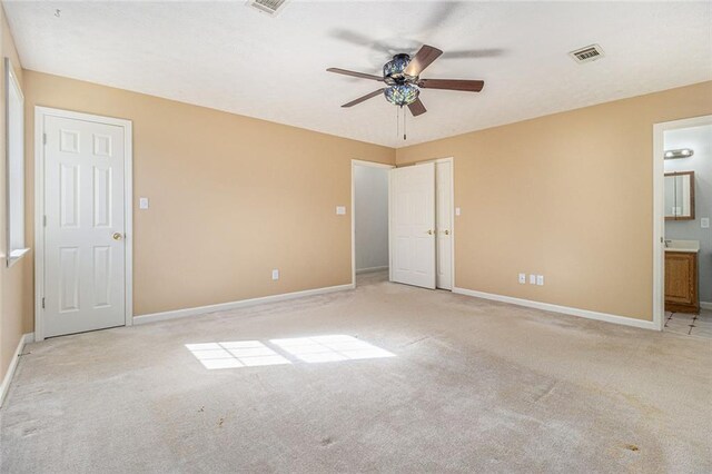 unfurnished bedroom featuring carpet, connected bathroom, visible vents, and baseboards