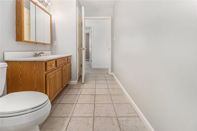 bathroom featuring baseboards, vanity, toilet, and tile patterned floors