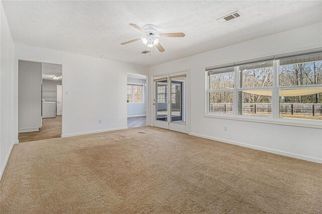 spare room with light carpet, a textured ceiling, and baseboards