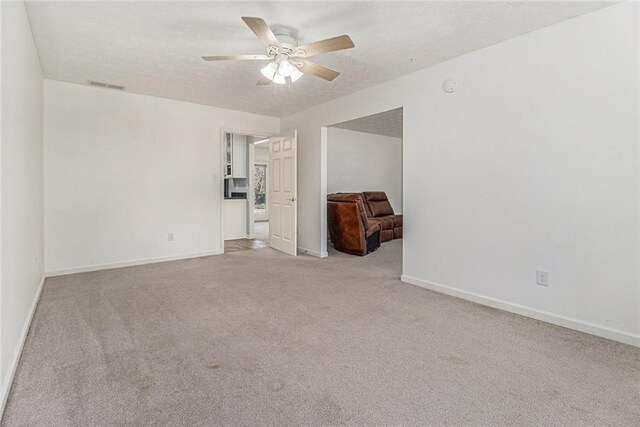 unfurnished room featuring light carpet, baseboards, visible vents, and a ceiling fan