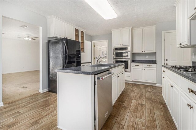 kitchen featuring stainless steel appliances, dark countertops, and light wood-style floors