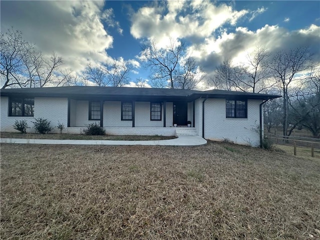 ranch-style house featuring covered porch and a front lawn