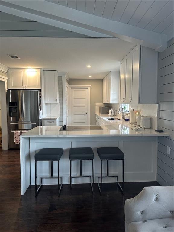 kitchen with white cabinets, a breakfast bar, stainless steel fridge, and kitchen peninsula