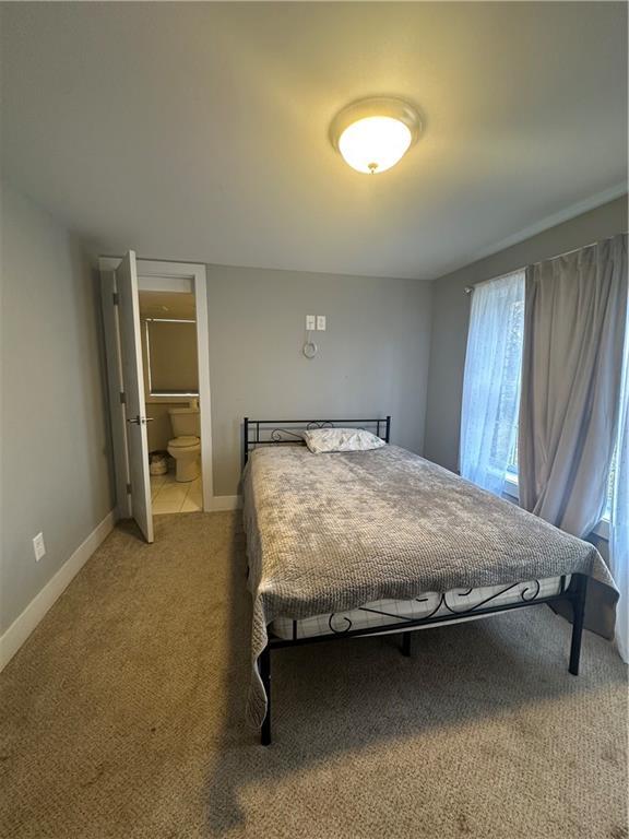 bedroom with ensuite bathroom and carpet flooring