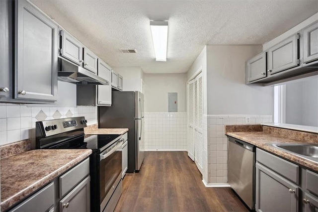 5555 Mountain Springs Cir, Stone Mountain, GA 30088 - kitchen featuring stainless steel appliances, gray cabinetry, dark wood-style flooring, under cabinet range hood, and tile walls