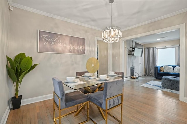 dining area featuring a notable chandelier, wood-type flooring, ornamental molding, and baseboards