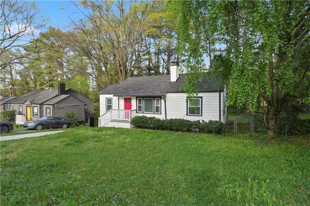 view of front of home featuring a chimney, fence, and a front lawn