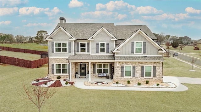 craftsman-style home featuring fence, a front lawn, and brick siding