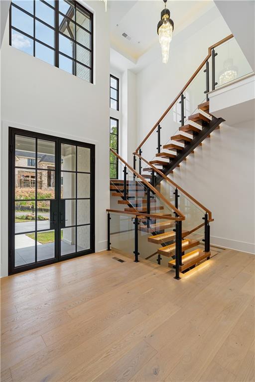 unfurnished living room with hardwood / wood-style floors, a notable chandelier, and a large fireplace