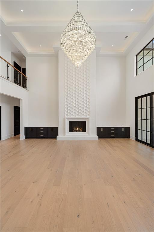 kitchen featuring decorative light fixtures, sink, a large fireplace, a chandelier, and light stone counters