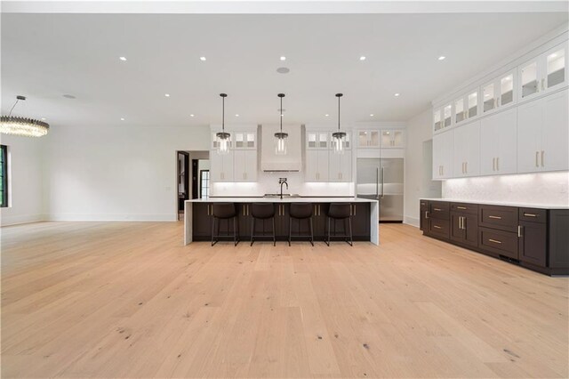 kitchen with tasteful backsplash, appliances with stainless steel finishes, light wood-type flooring, and wall chimney range hood