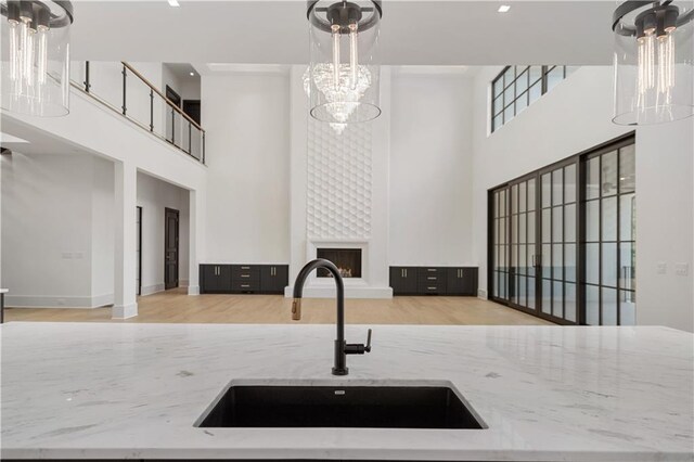 unfurnished living room featuring an inviting chandelier, a high end fireplace, a tray ceiling, and wood-type flooring