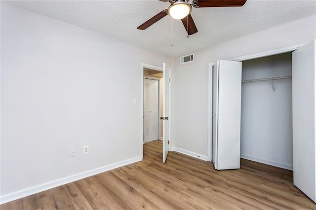 unfurnished bedroom featuring a textured ceiling, ceiling fan, a closet, and light hardwood / wood-style floors