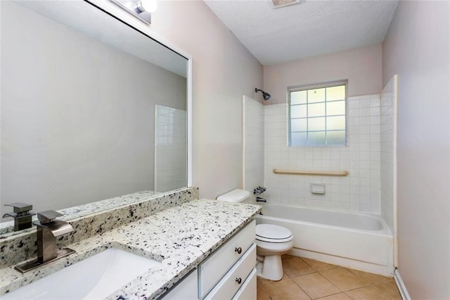 full bathroom featuring a textured ceiling, tiled shower / bath, tile patterned floors, vanity, and toilet