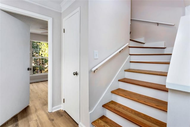 stairway featuring a textured ceiling, ornamental molding, and hardwood / wood-style floors