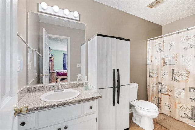 bathroom featuring a textured ceiling, toilet, vanity, visible vents, and tile patterned floors