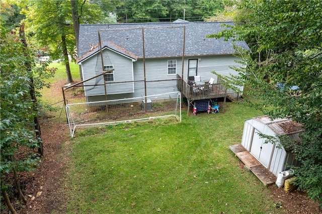 back of house with a yard, a storage unit, a shingled roof, an outdoor structure, and a wooden deck